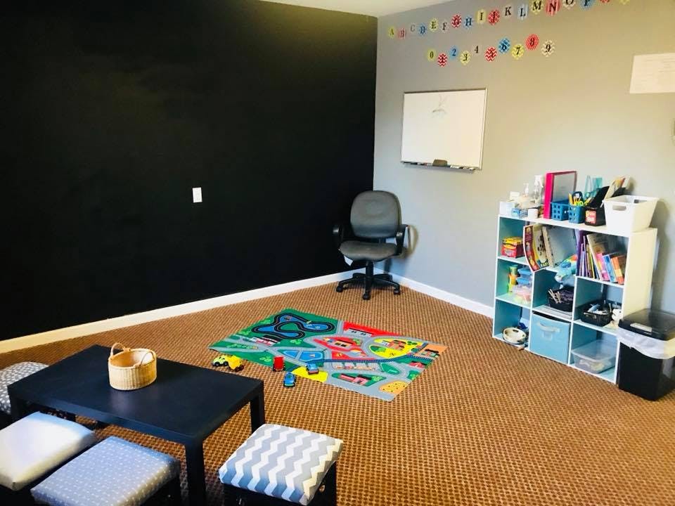 Playroom with a black wall, gray wall, and a colorful rug with toys on the floor