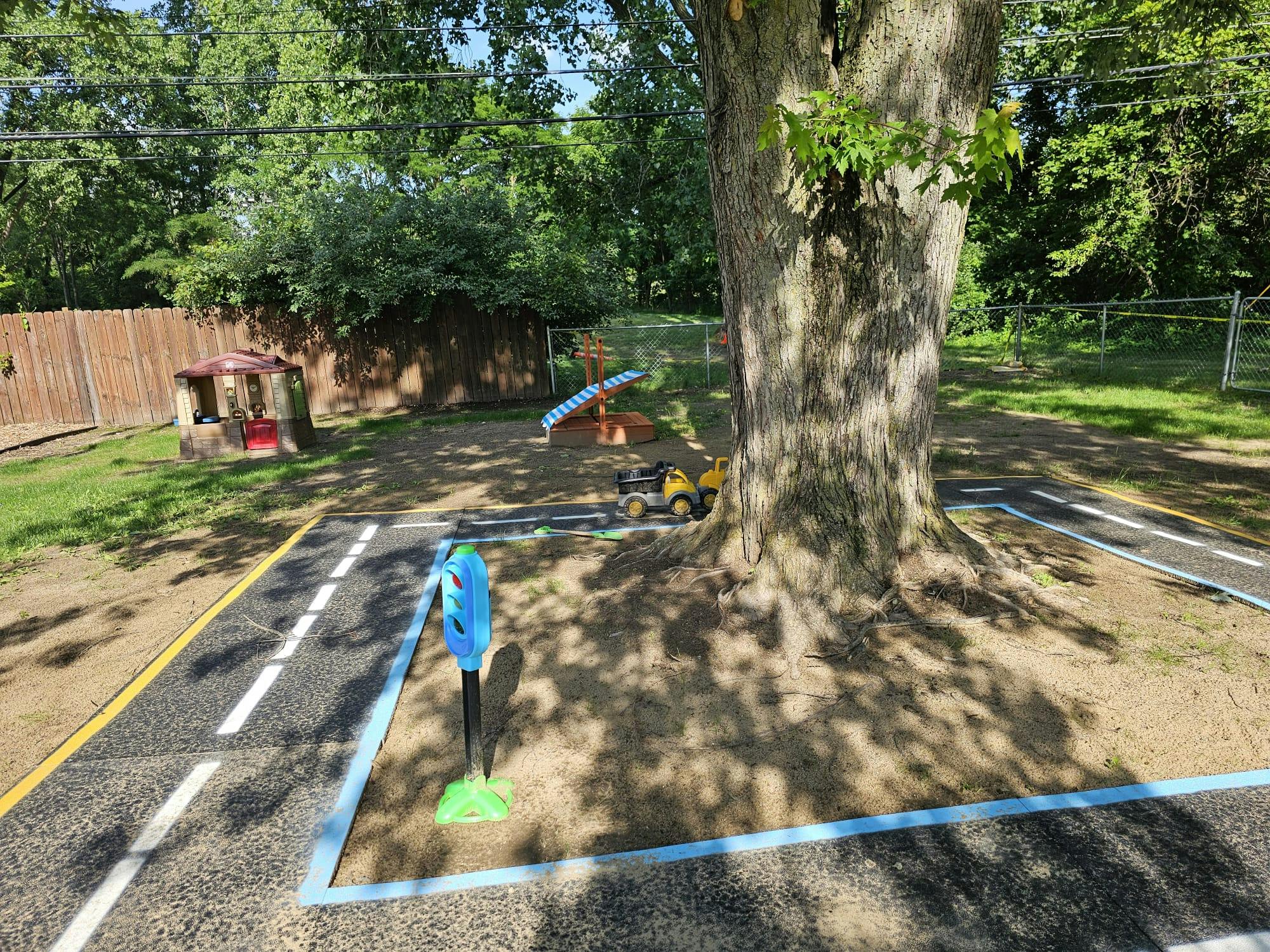 Playground area with a playhouse and a miniature road painted on the ground