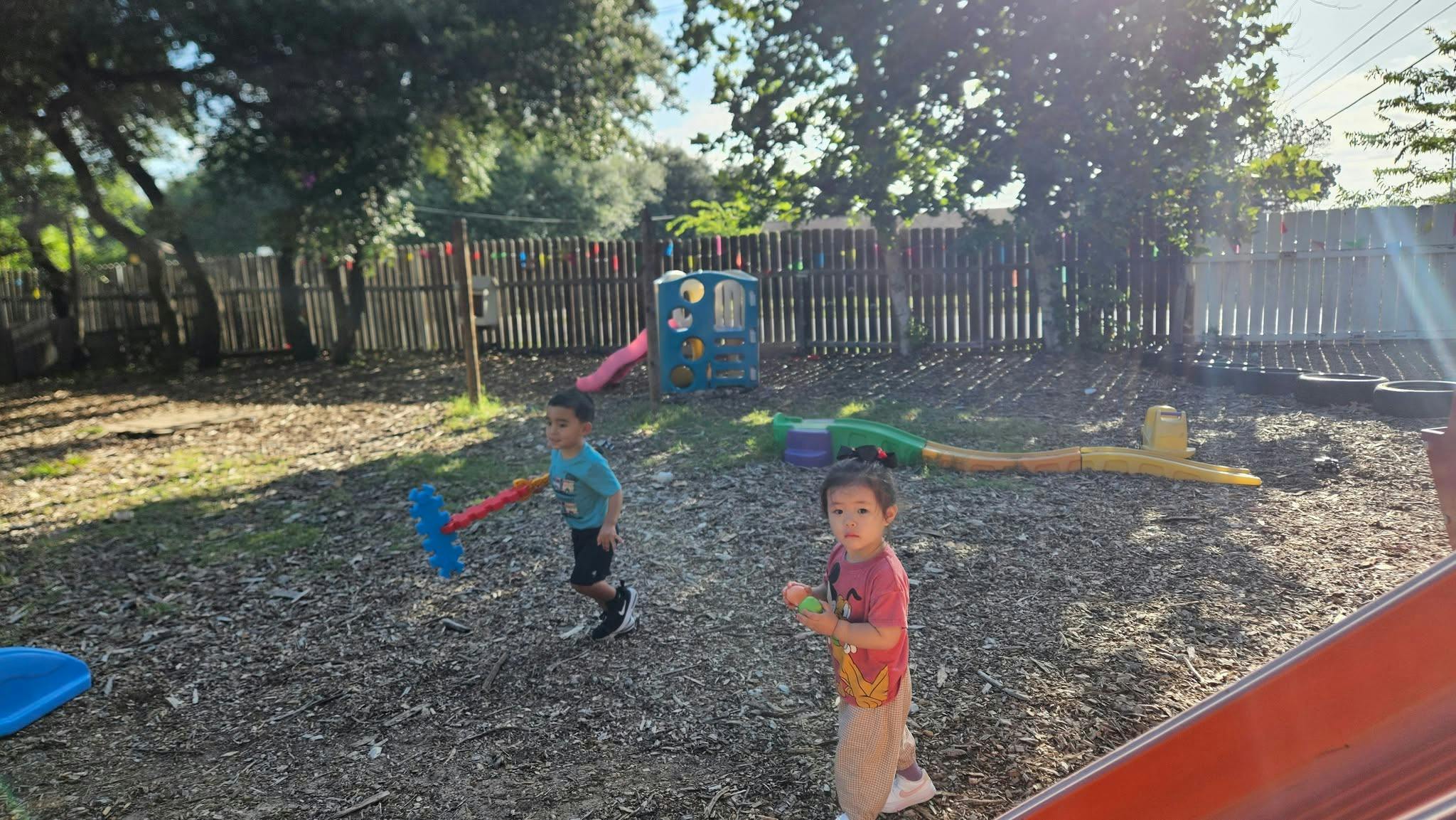 Two children playing in a backyard playground