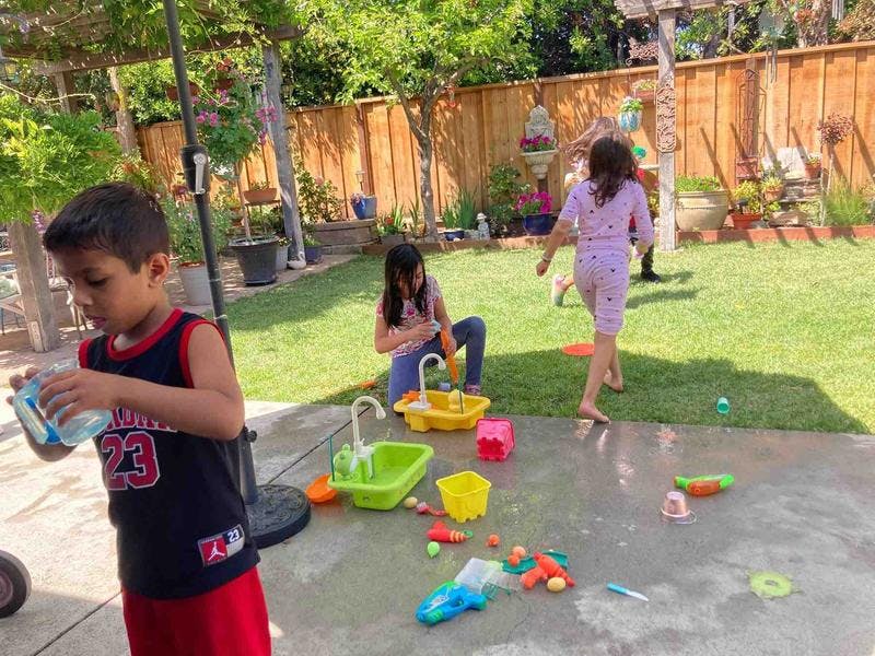 Children playing with water toys in a backyard