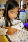 Child writing on paper with a pencil