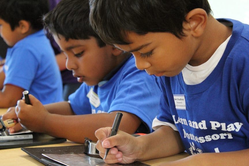 Children writing at desks in a classroom