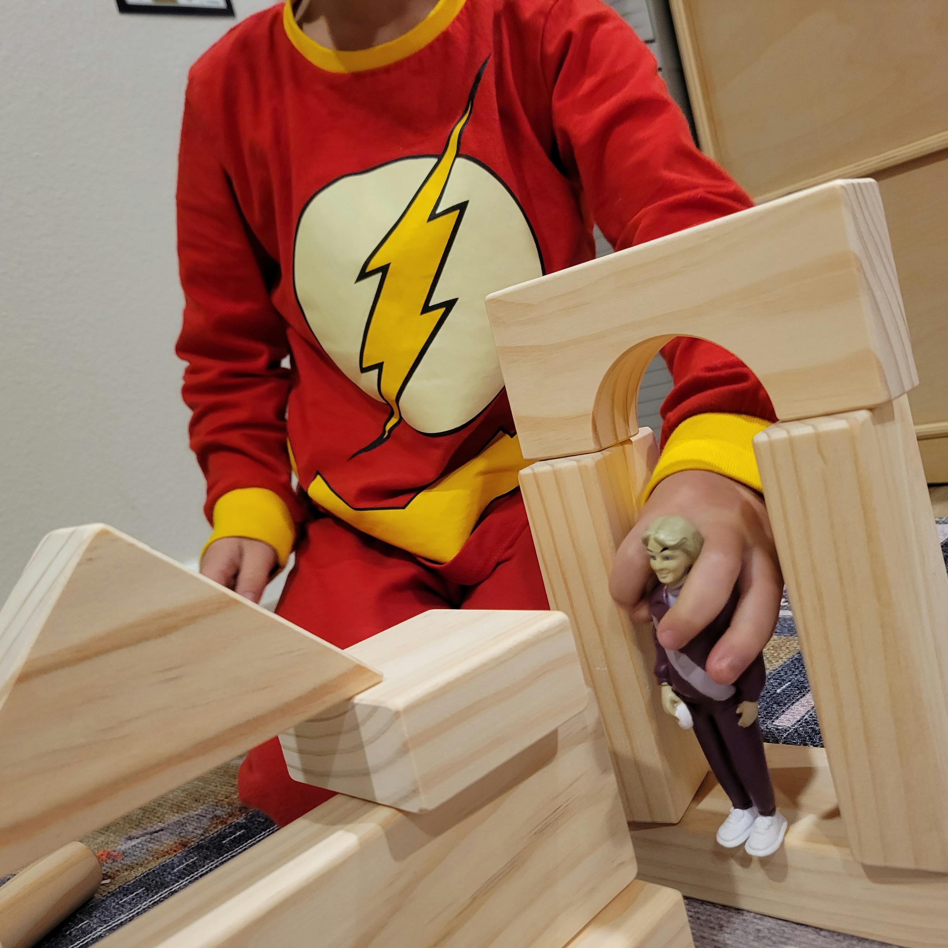 Child in red shirt playing with wooden blocks and a small figure