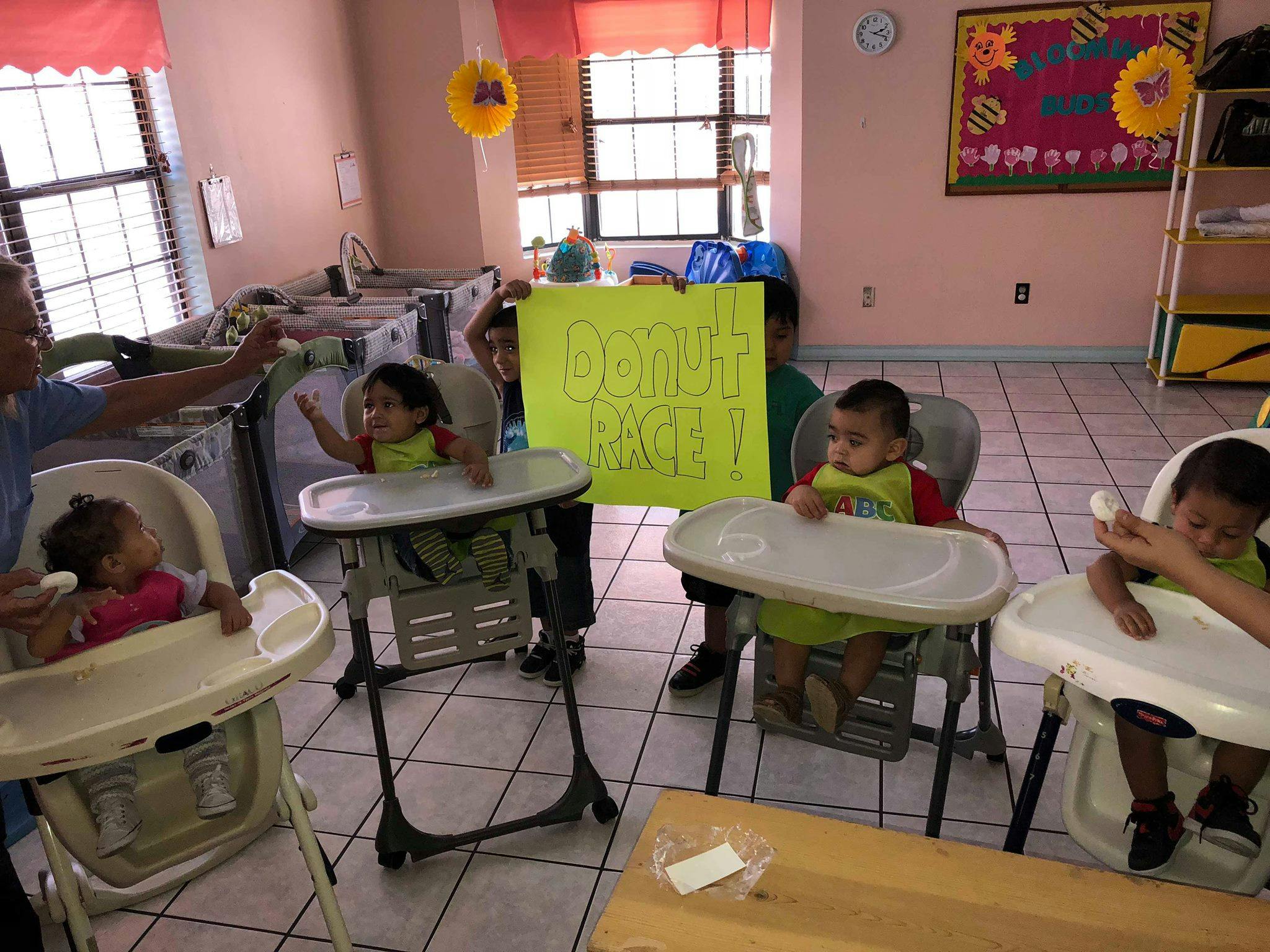 Adult interacting with children in high chairs in a room