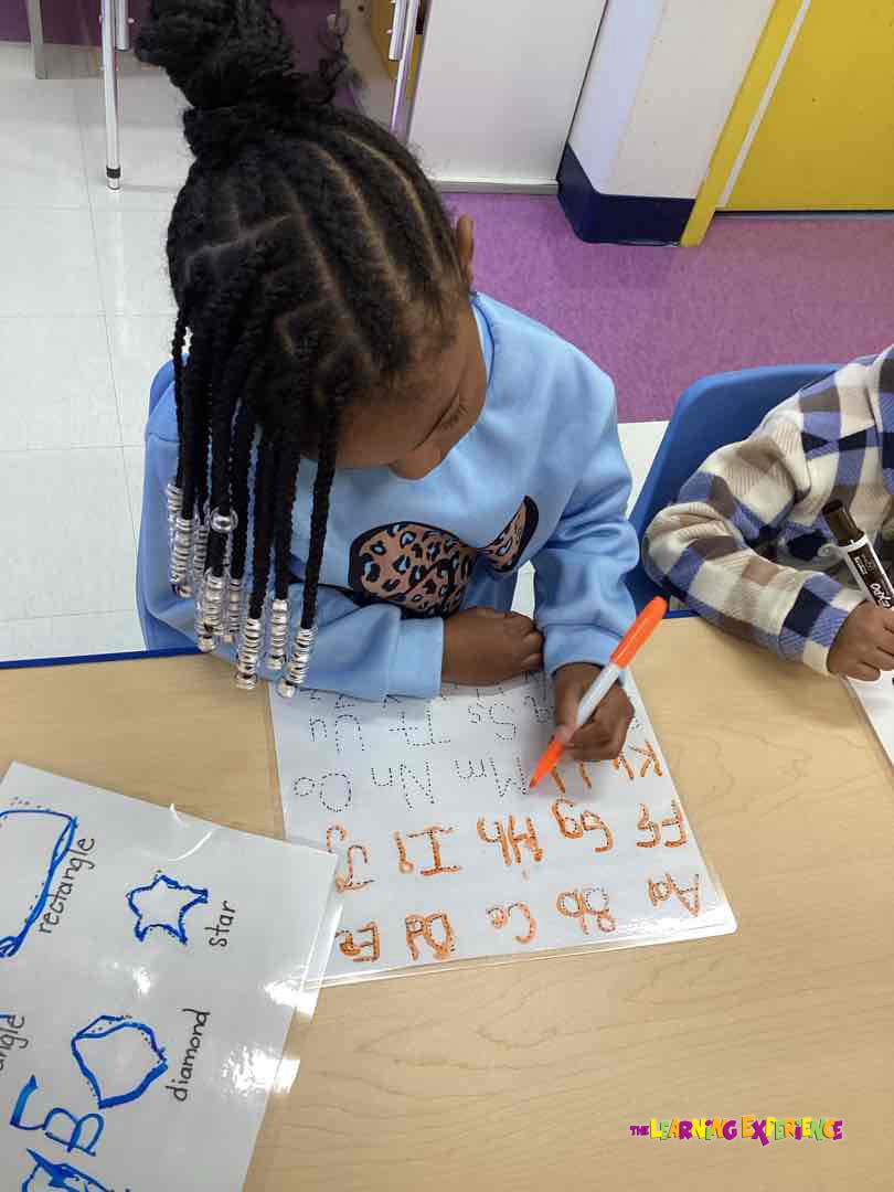 Child tracing letters of the alphabet on a worksheet