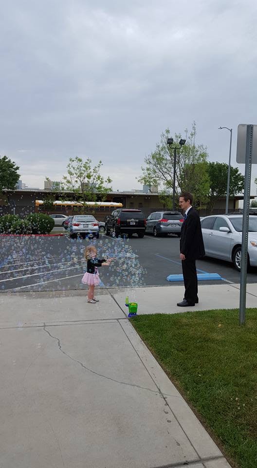 Child blowing bubbles towards a person in a suit