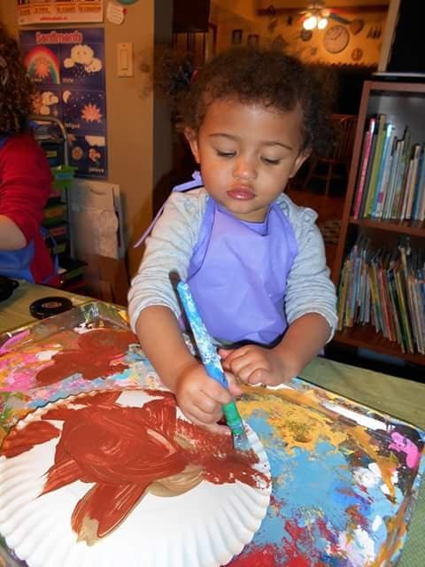 Child painting on a paper plate with a paintbrush