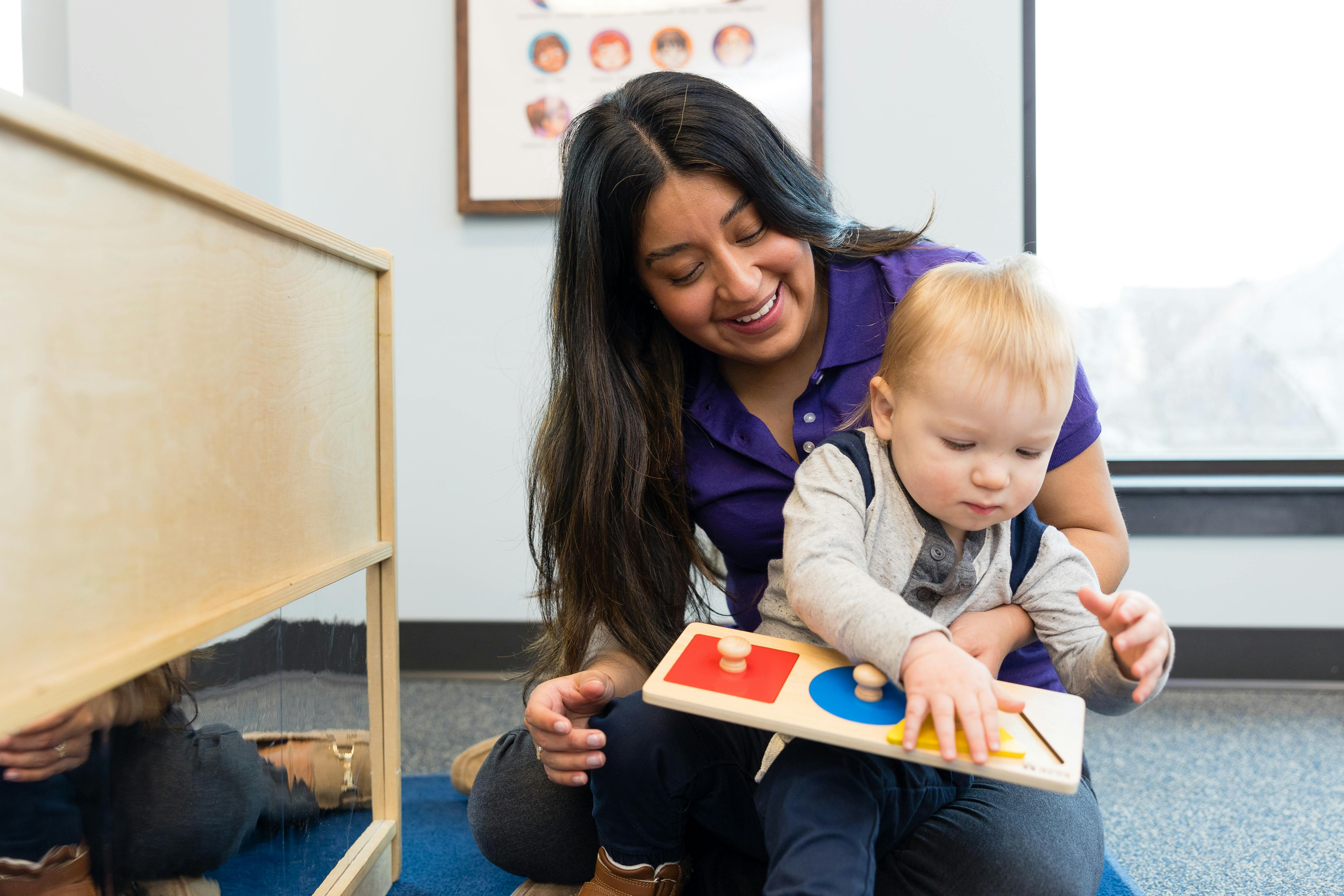 Adult and child playing with a shape puzzle on the floor