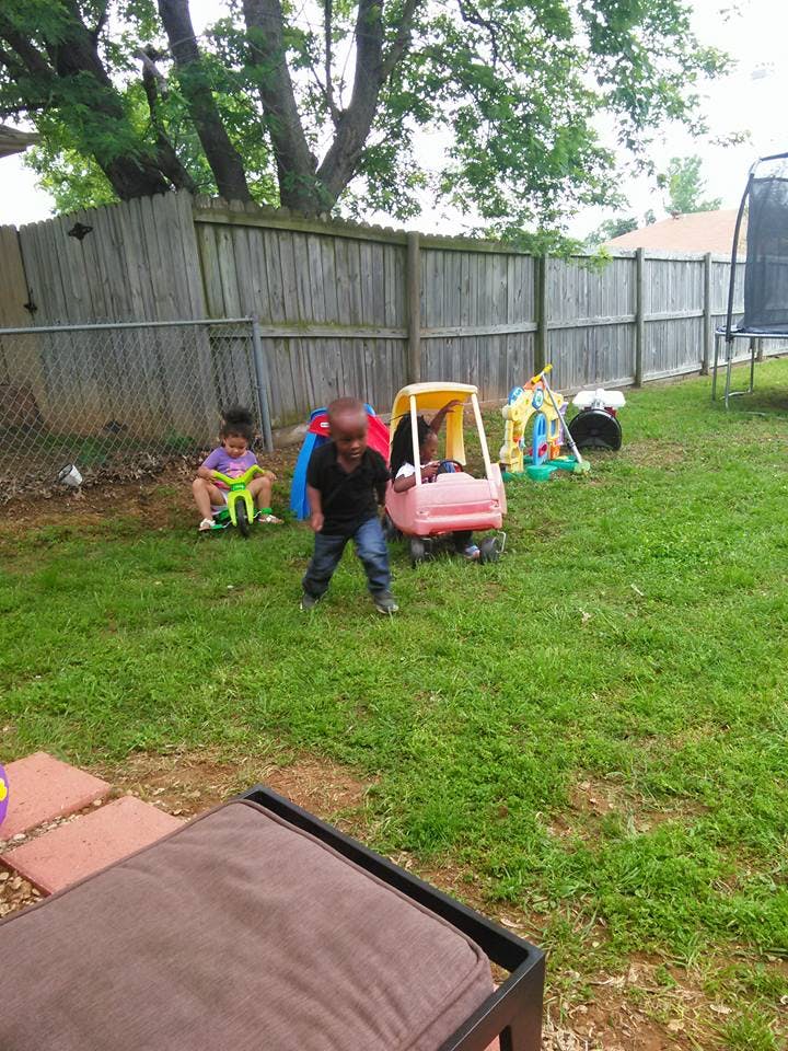 Two children playing in a grassy backyard with toys
