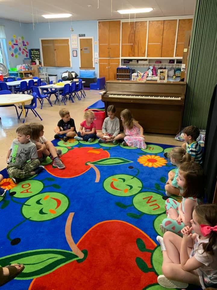 Children sitting on a colorful rug in a classroom
