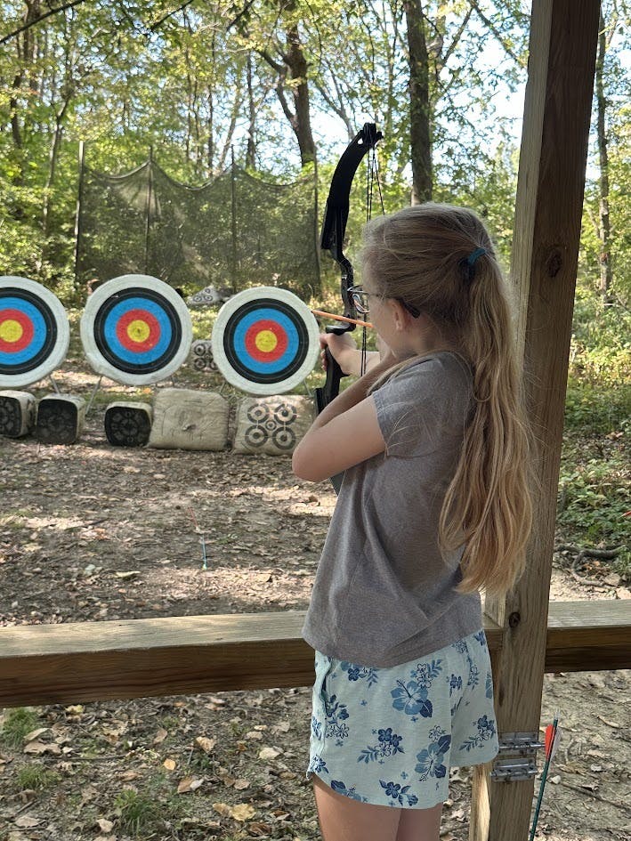 Child aiming a bow and arrow at archery targets