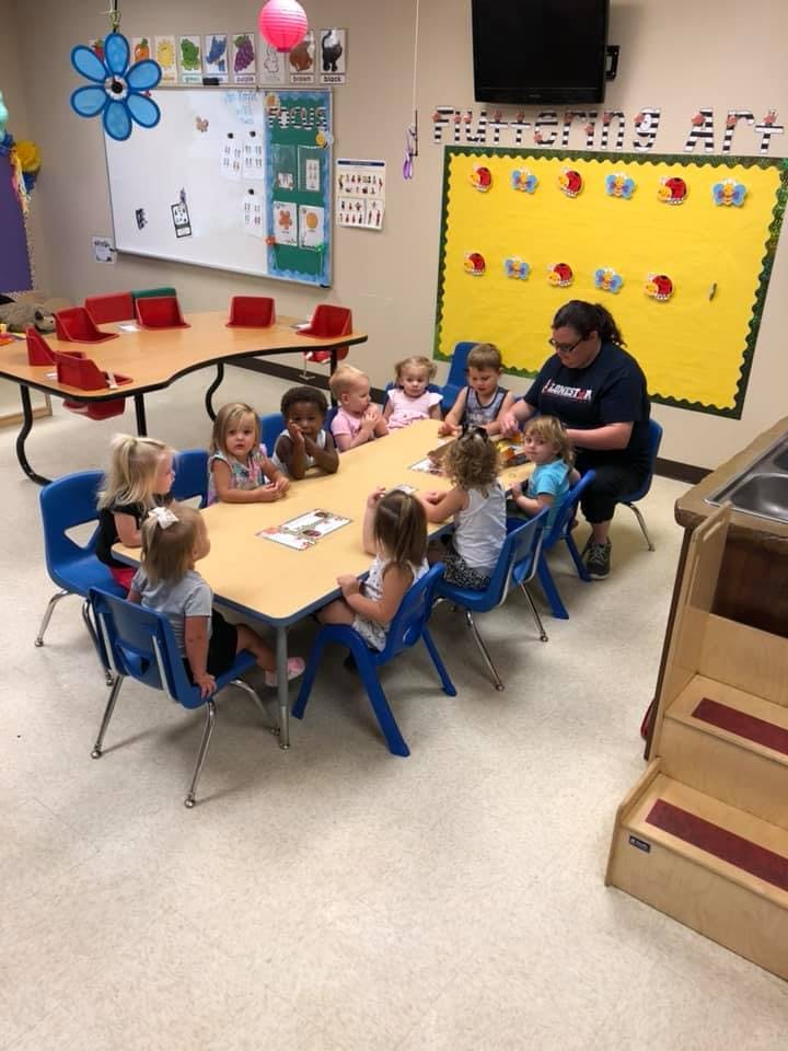 Adult and multiple children sitting around a table in a classroom