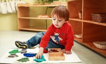 Child playing with felt shapes on a mat