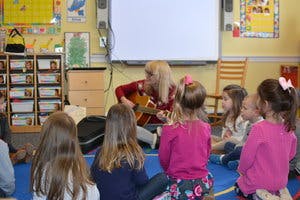 Person playing guitar for children in a classroom