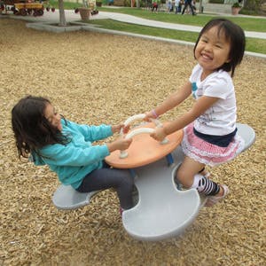 Two children on a playground seesaw