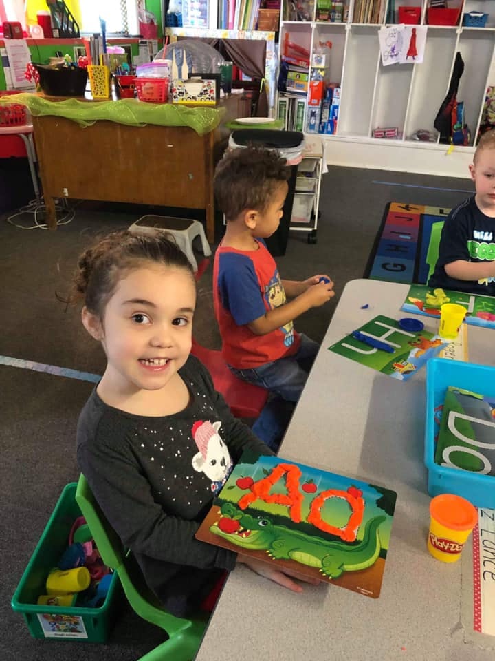 Child holding a puzzle with the letter A on an alligator