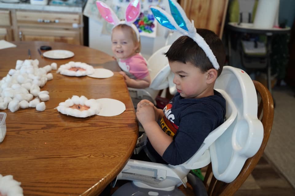 Two children wearing bunny ears at a table with craft supplies