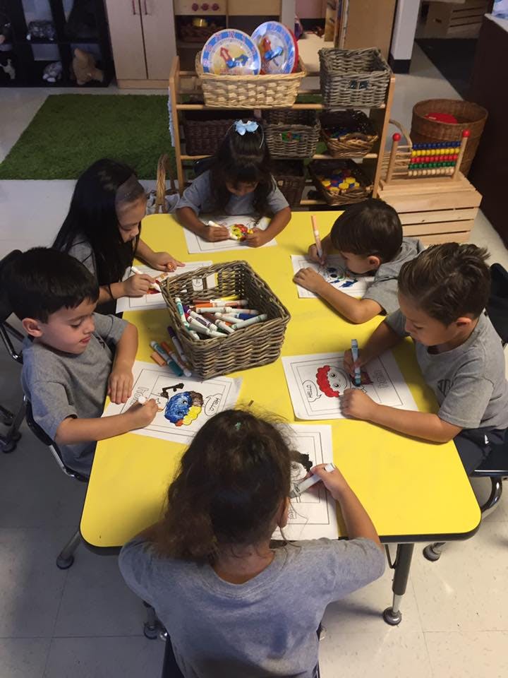 Children coloring at a yellow table