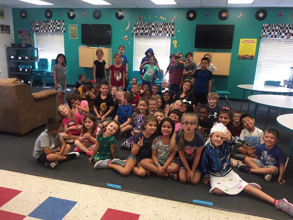 Group of children and teens posing in a classroom