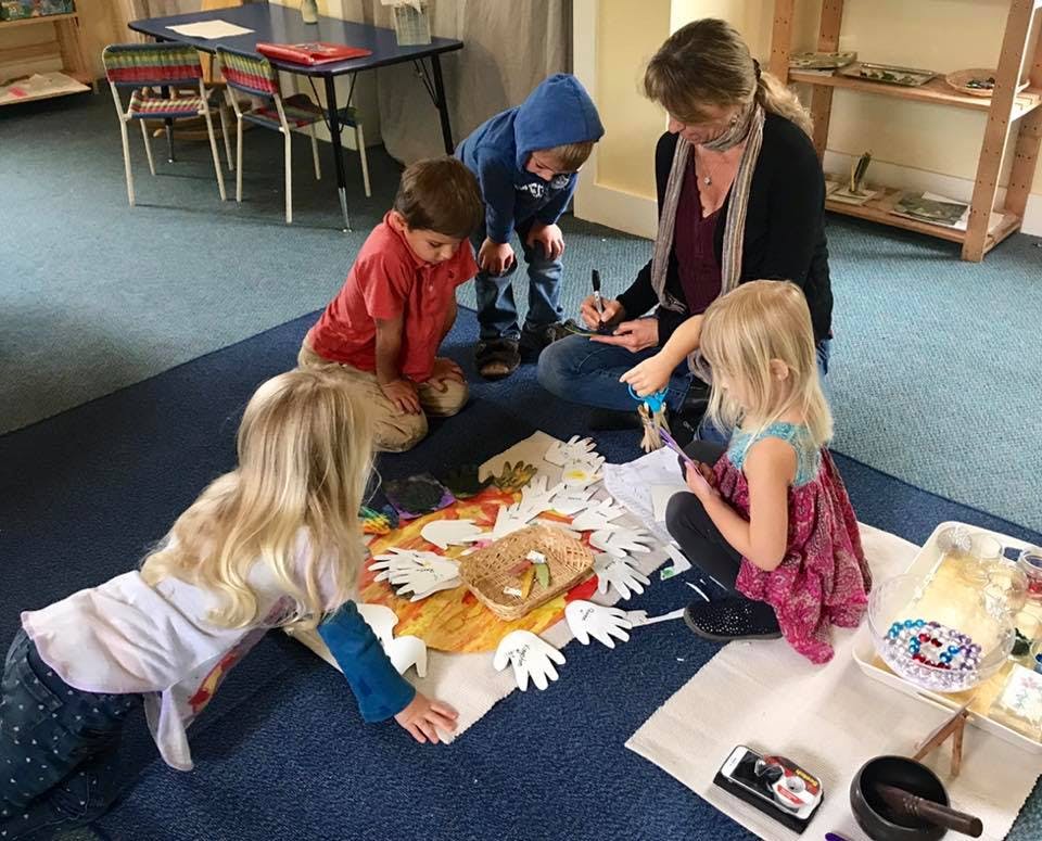 Adult and children on floor doing craft activity