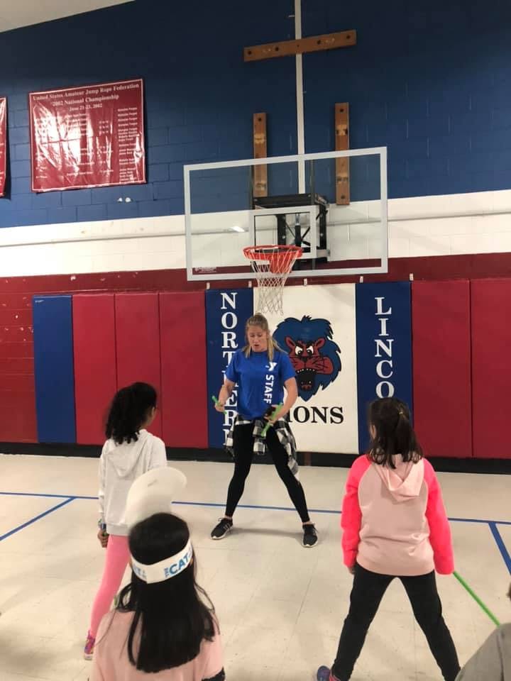 Person leading children in an activity in a gymnasium