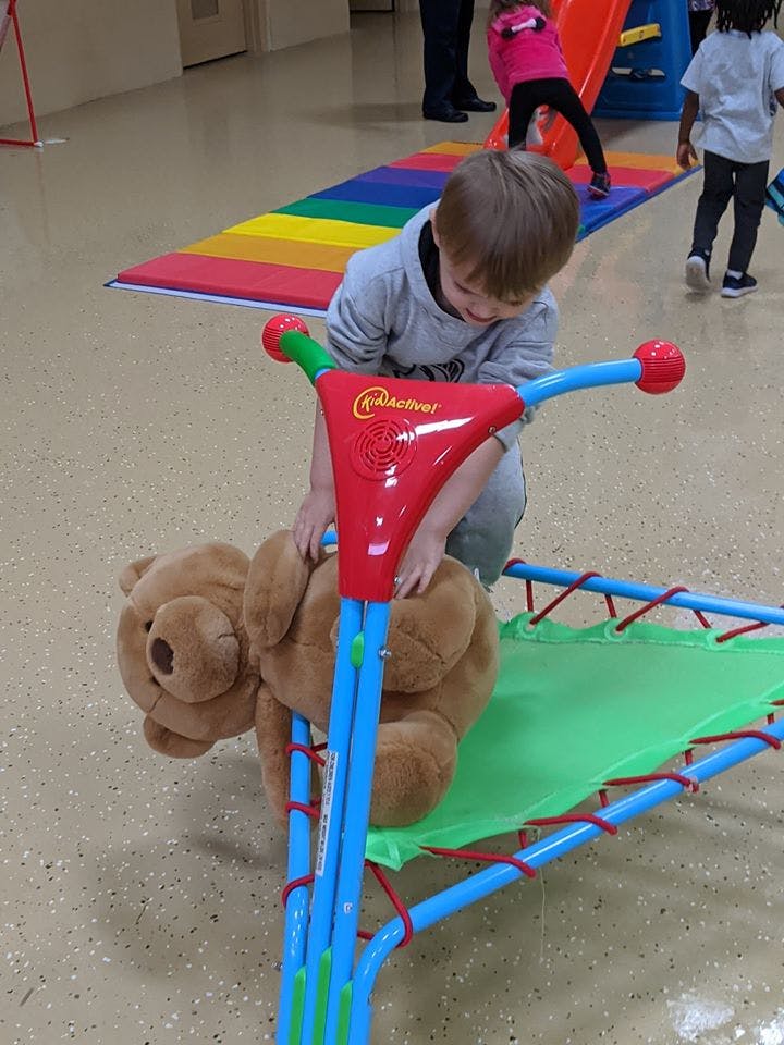 Child playing with a teddy bear on a small trampoline