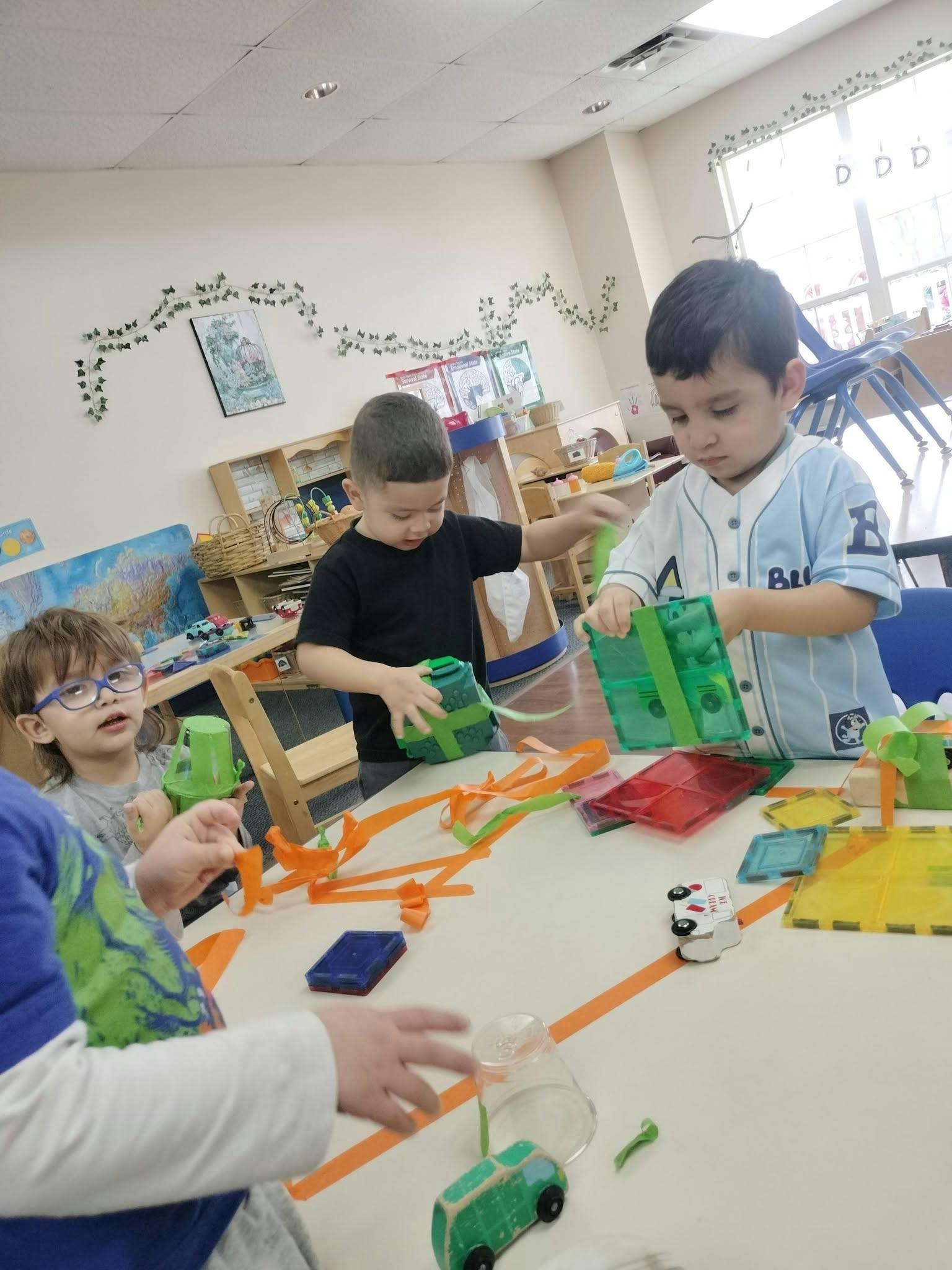Children playing with magnetic tiles and ribbon in a classroom