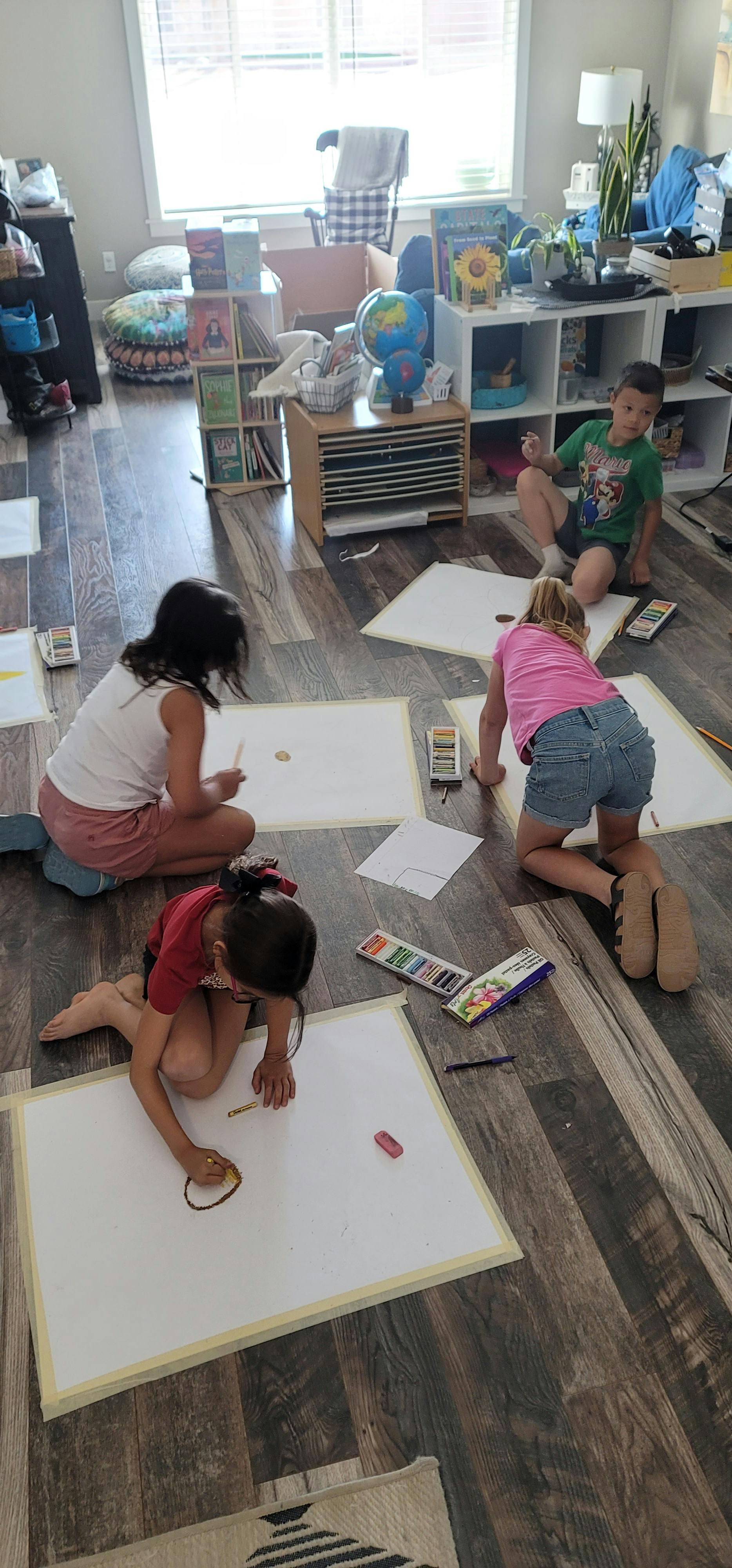 Children drawing on paper on the floor