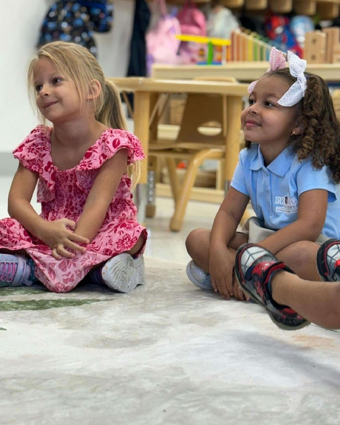 Two children sitting on the floor in a classroom
