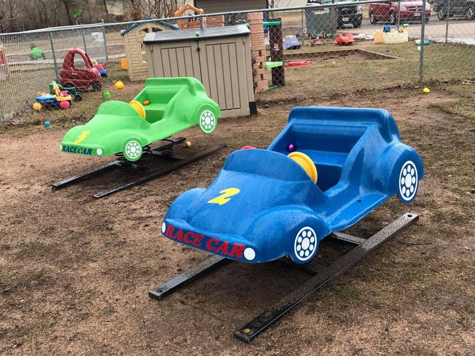 Two spring riders shaped like race cars, one blue and one green
