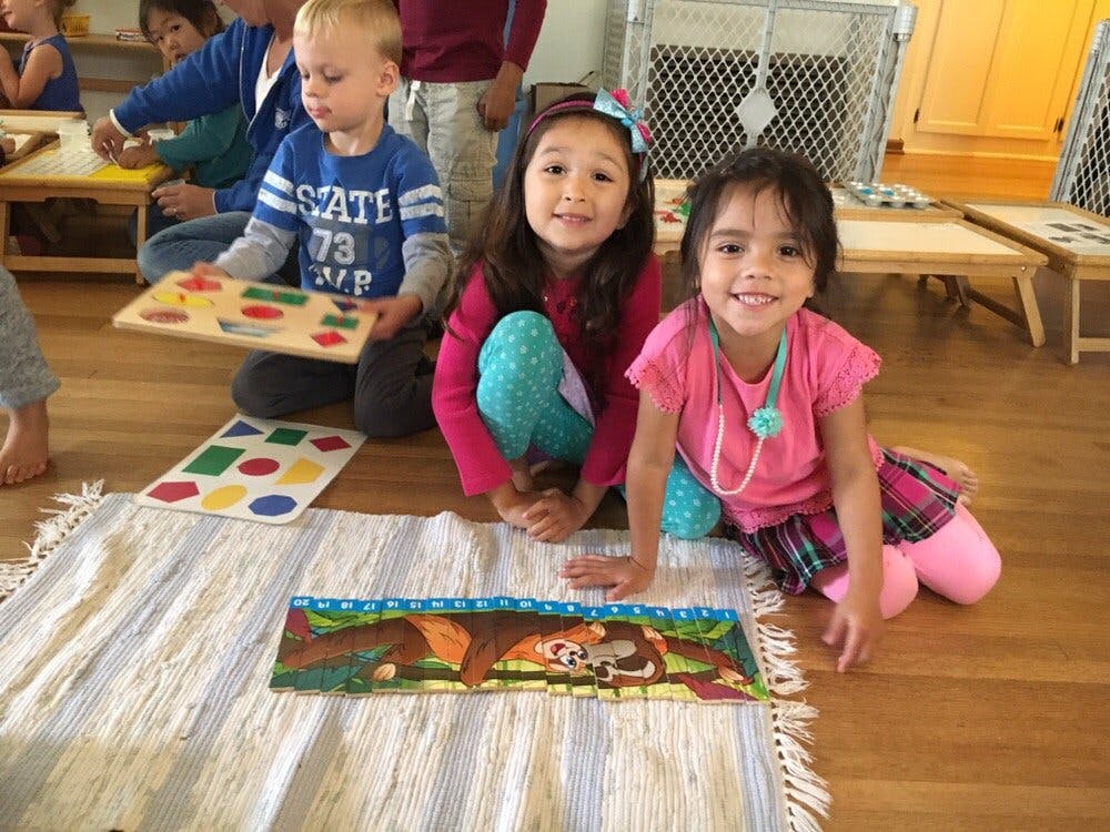 Three children playing with puzzles on the floor