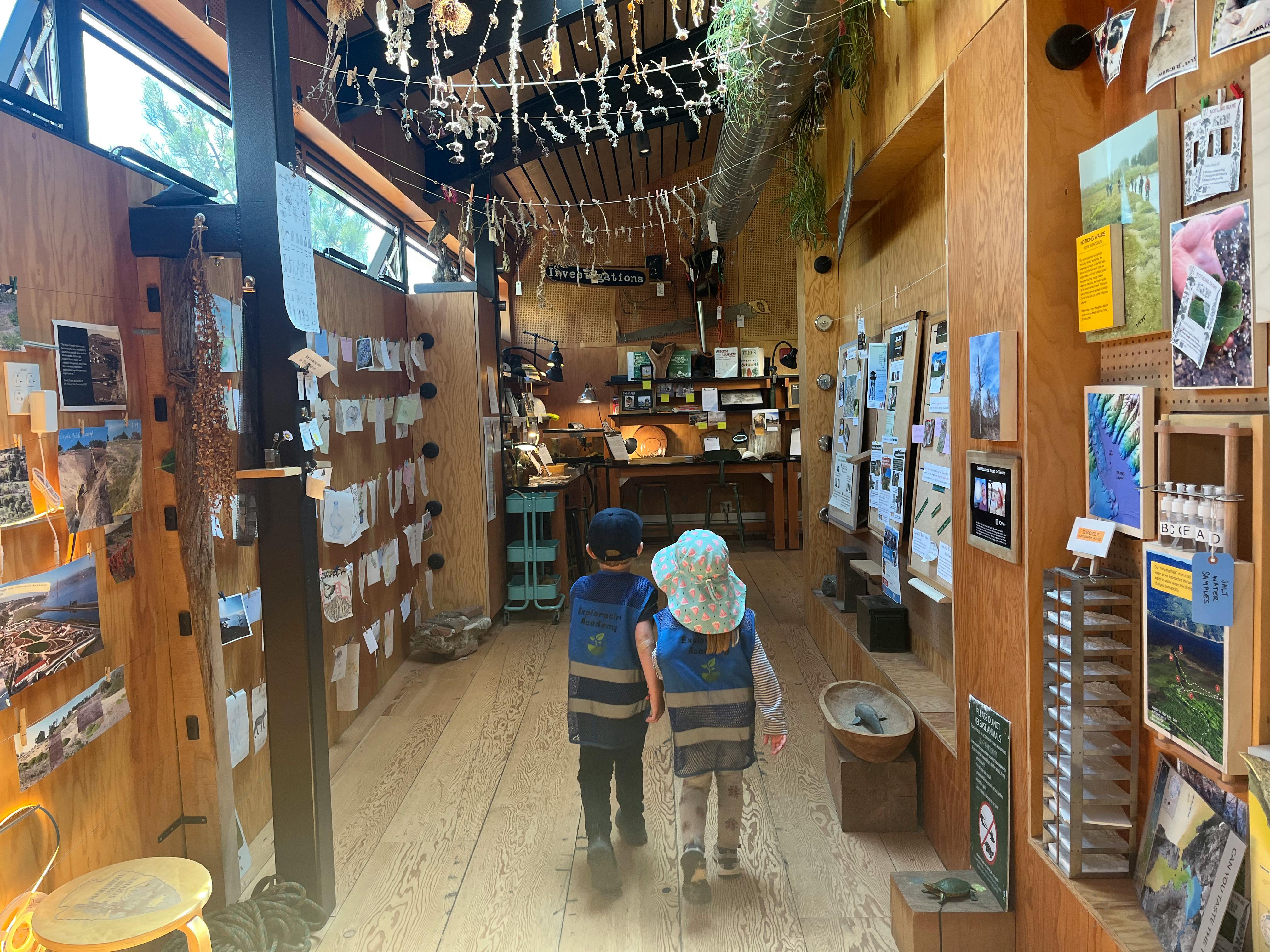 Two children walking through a store with wooden walls and displays