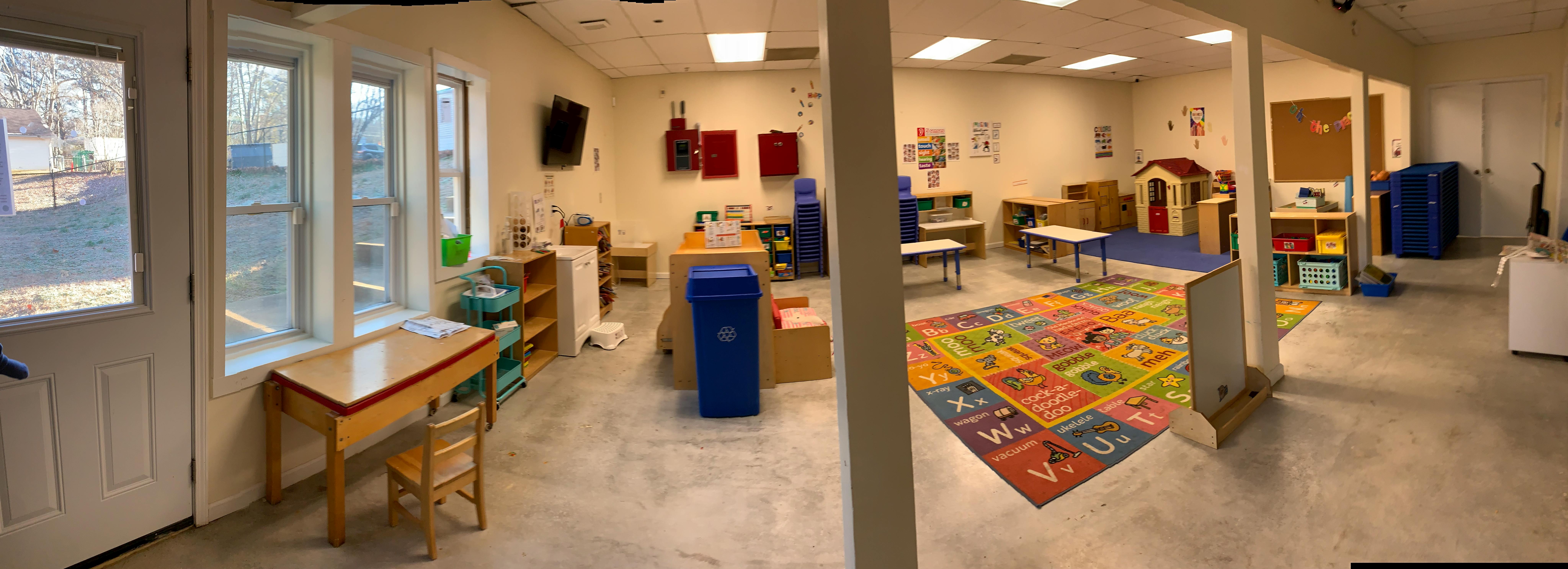 Playroom with colorful rug, small tables, and play structures