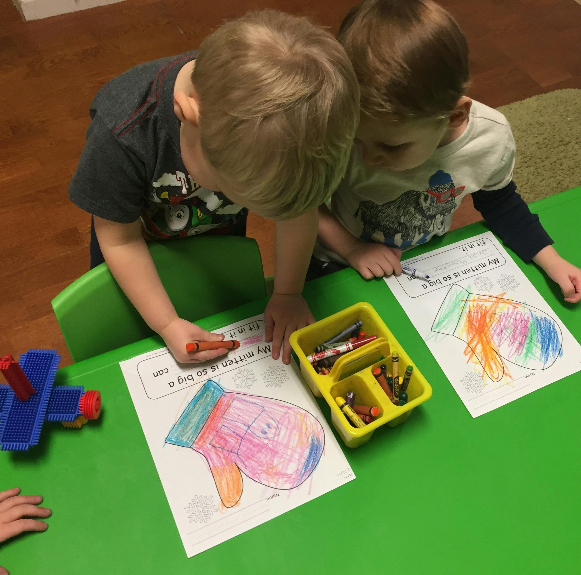Two children coloring at a green table
