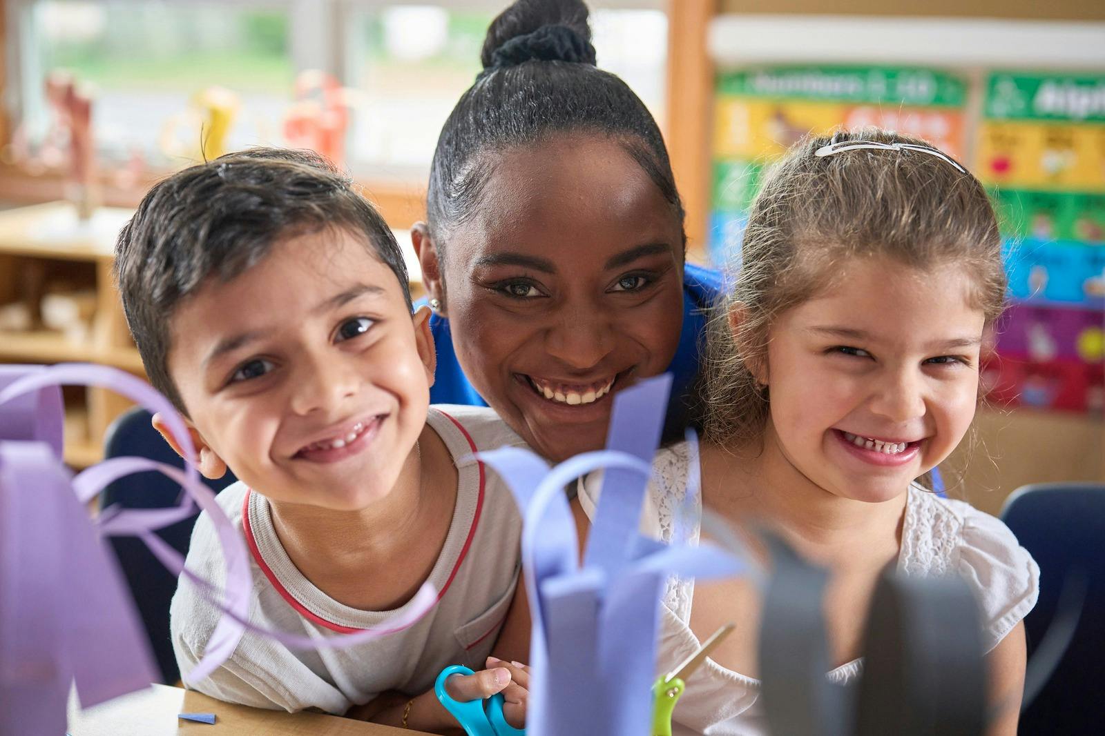 Adult and two children smiling in a classroom
