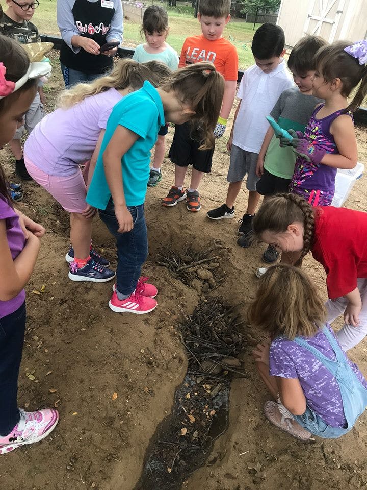 Children gathered around a muddy trench in the ground