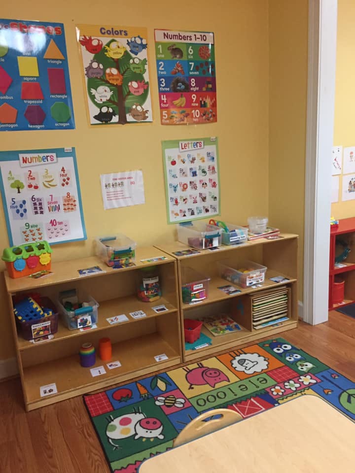 Classroom with educational posters, shelves of toys, and a colorful rug