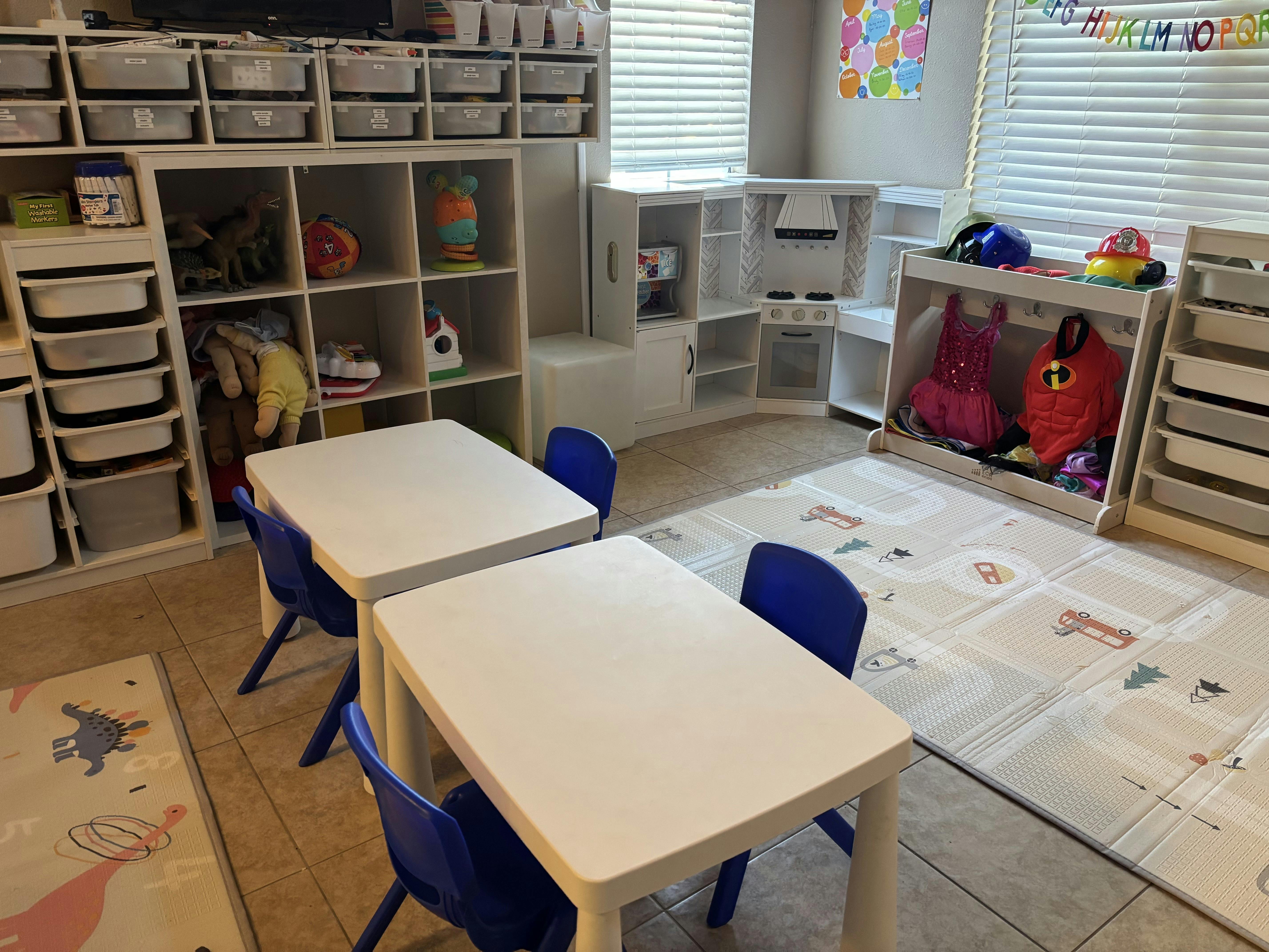 Two small white tables with blue chairs in a classroom