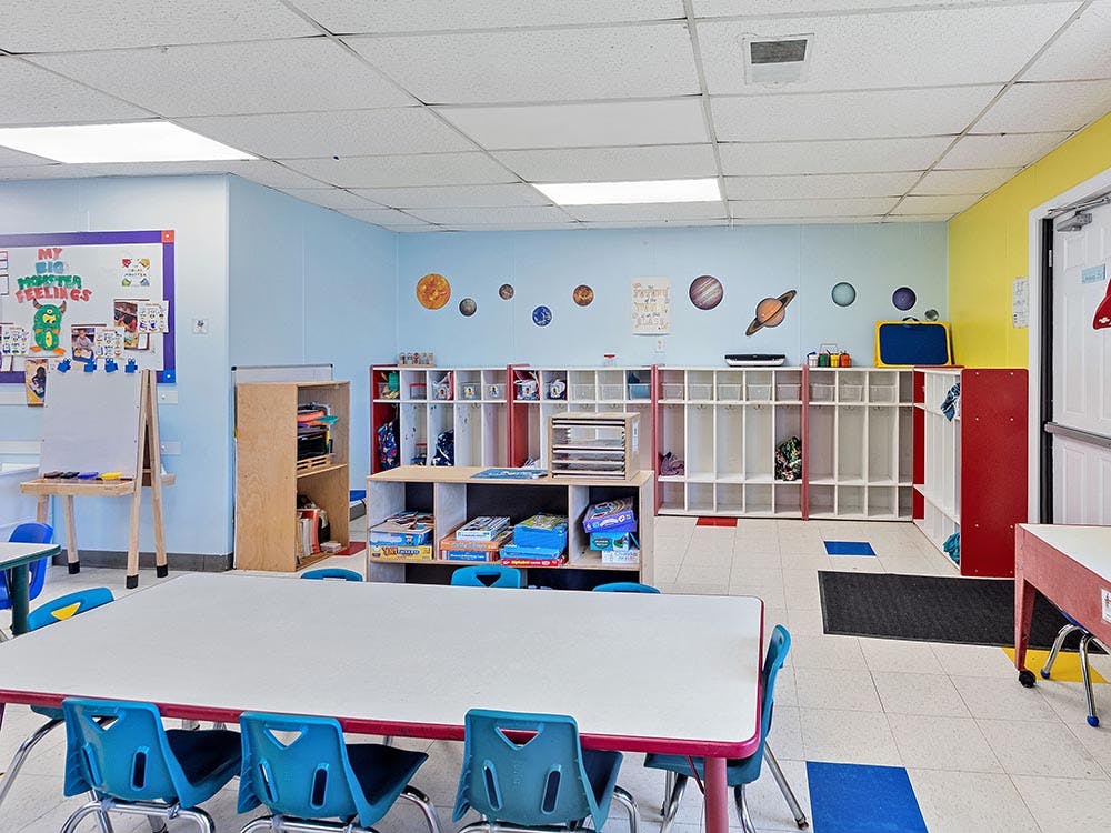 Classroom with tables, chairs, cubbies, and planet decorations
