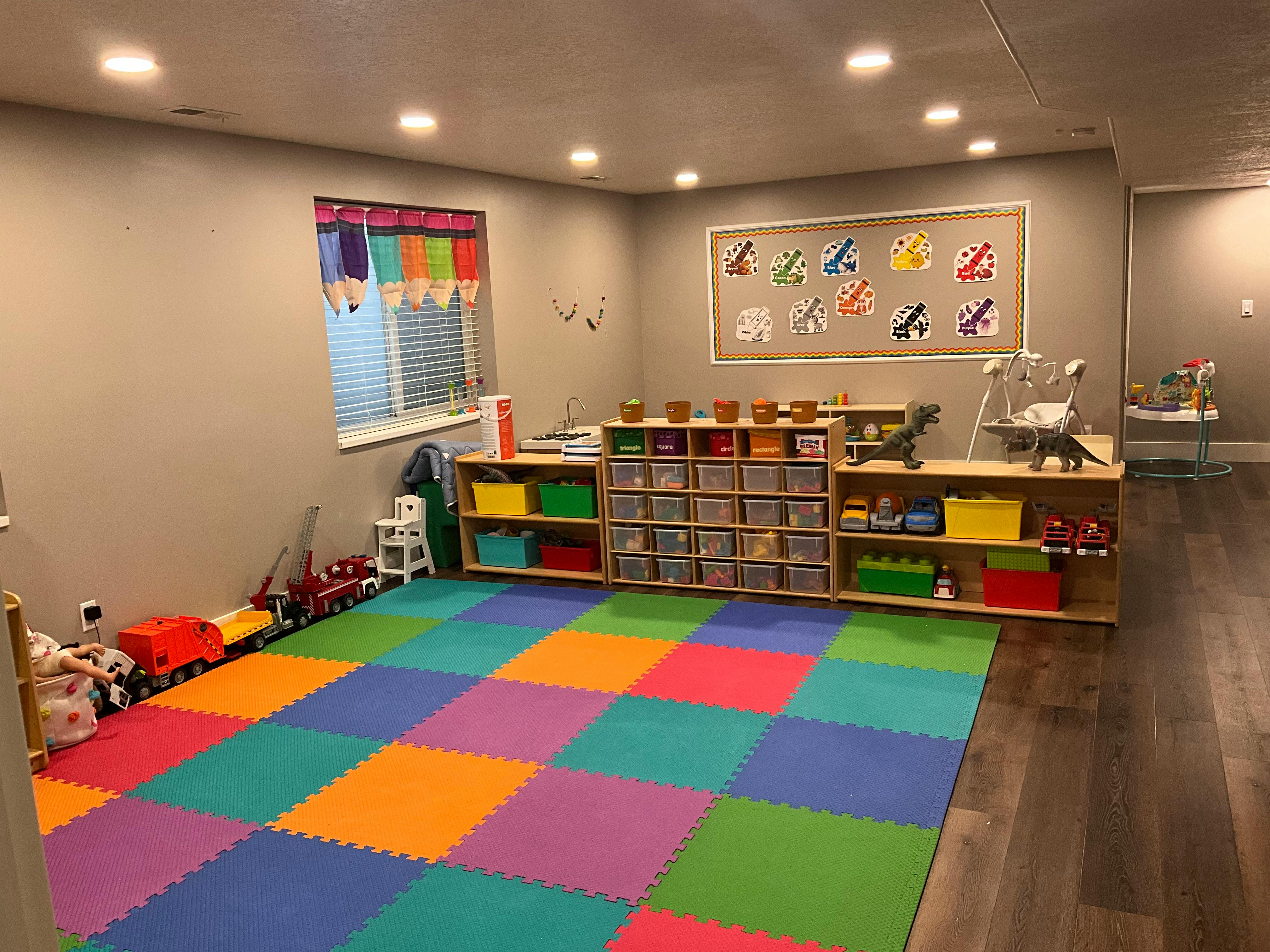 Playroom with colorful floor mats, toy shelves, and window