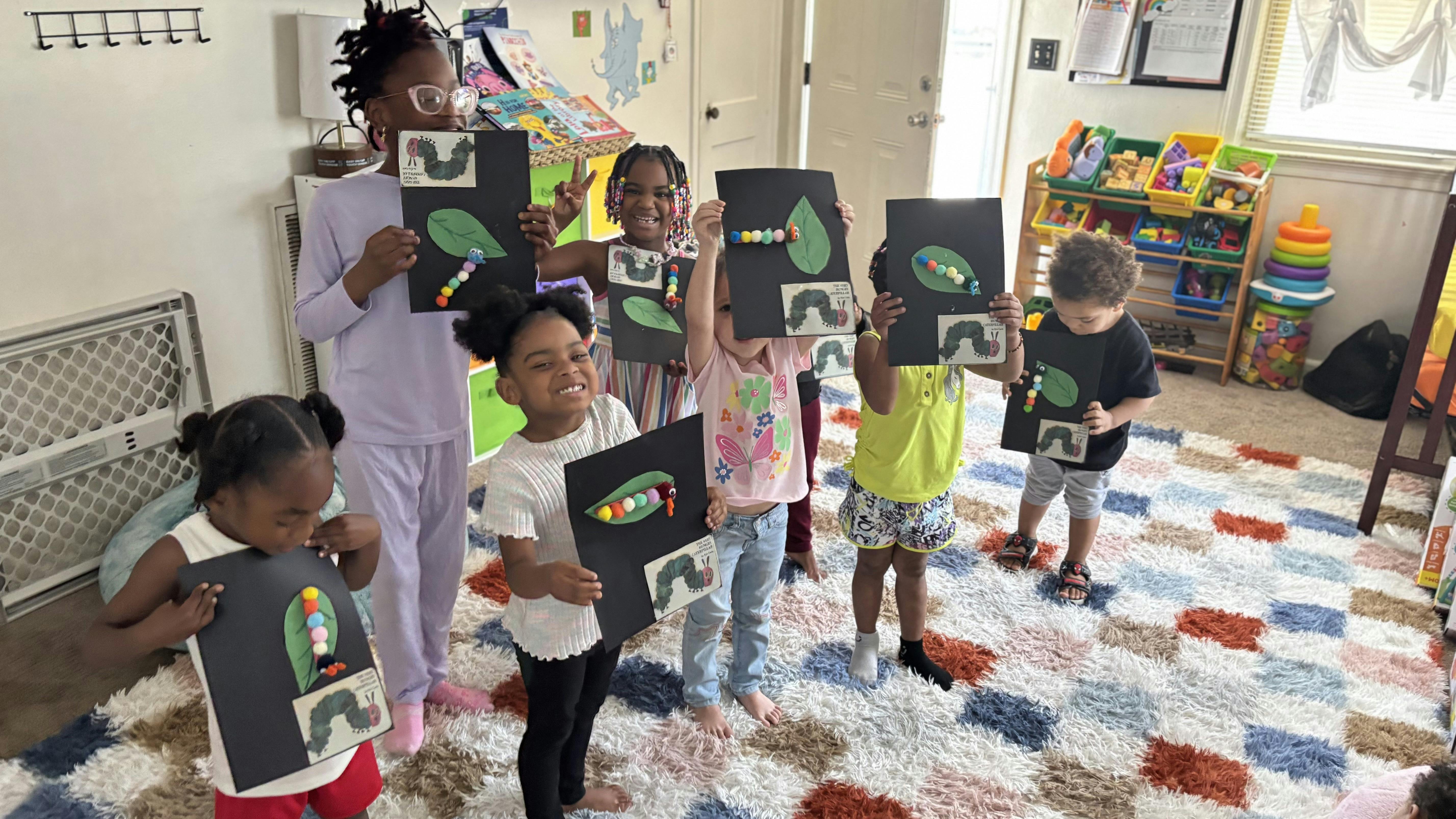 Group of children holding up caterpillar craft projects with leaves and leaves