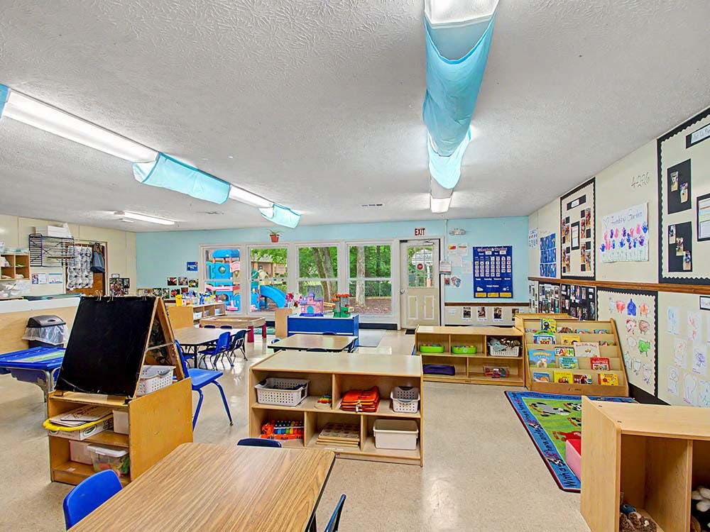 Empty colorful preschool classroom with small tables, chairs, and shelves