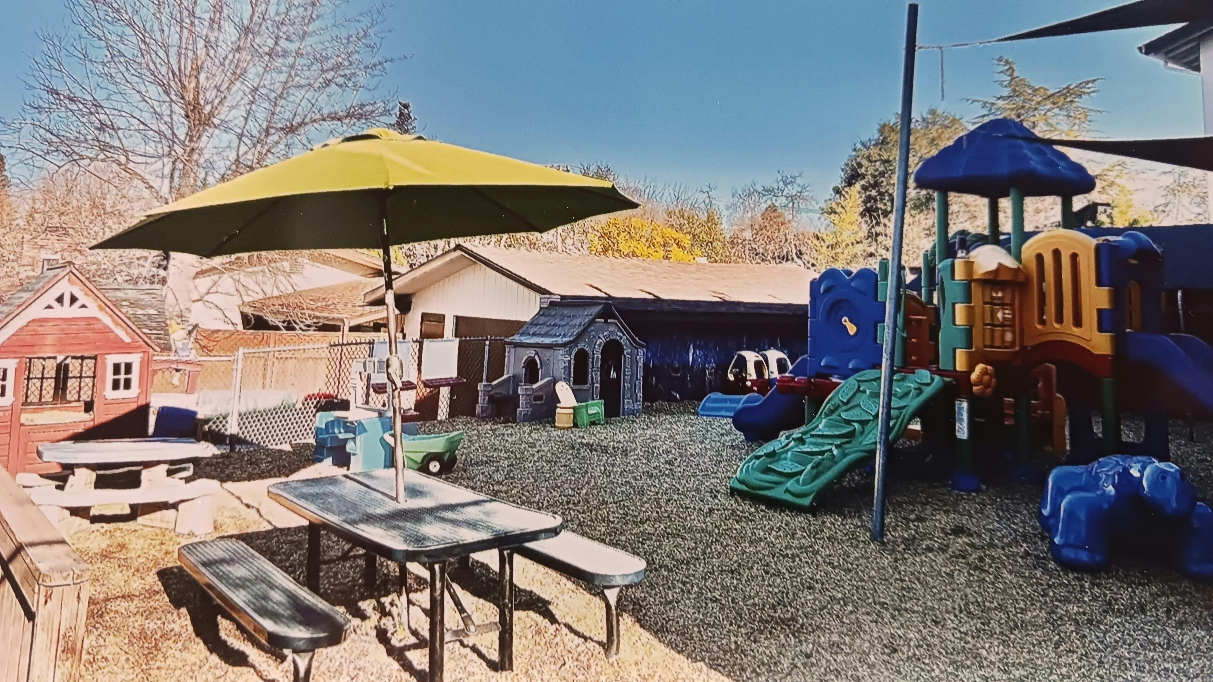 Outdoor playground with slides, playhouses, and picnic tables