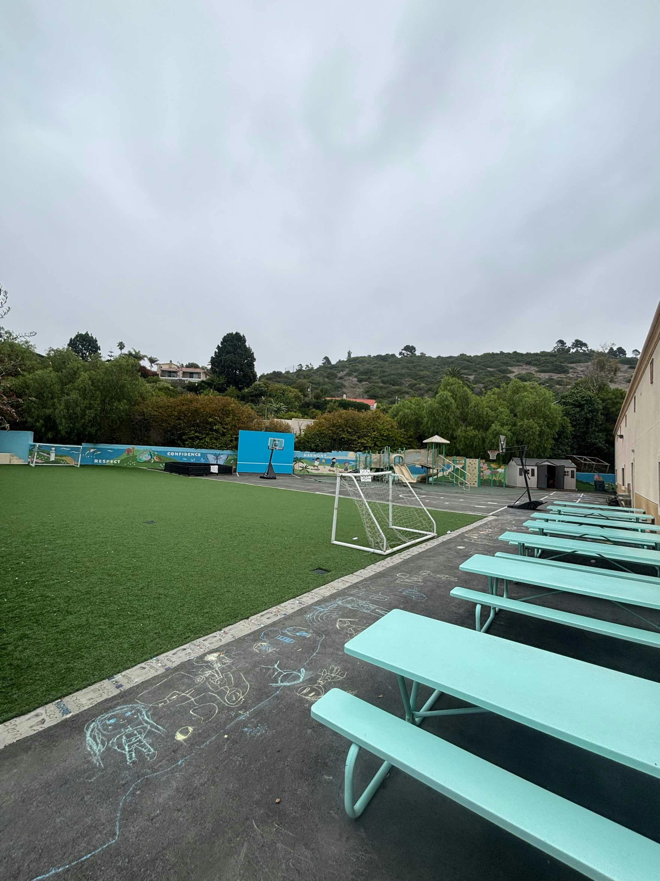 Empty outdoor school playground with picnic tables and a soccer goal