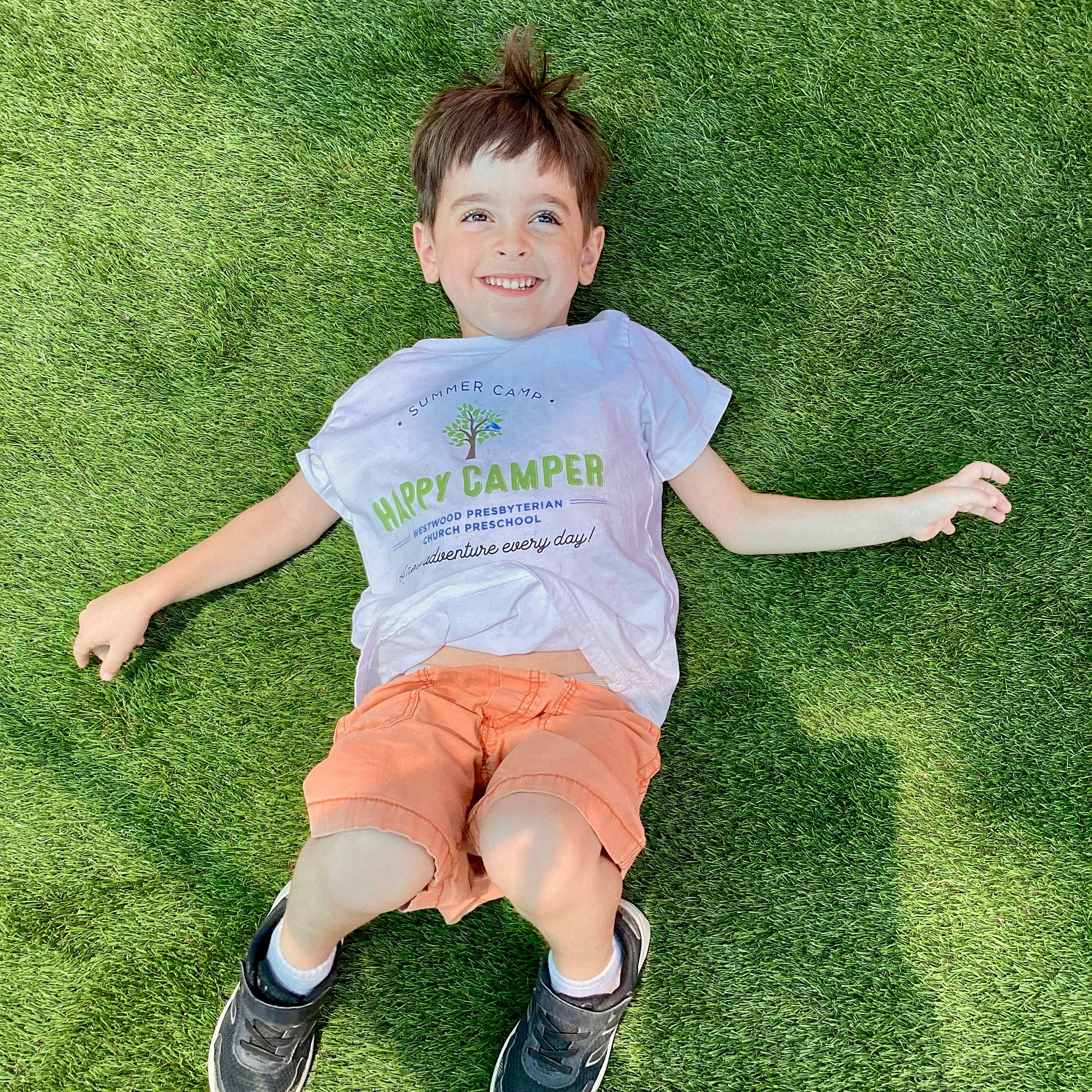 Child lying on green grass