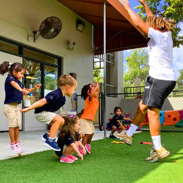 Adult and children playing outdoors on artificial grass