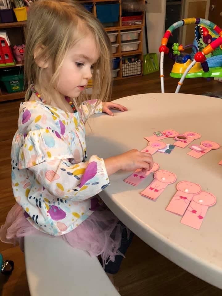 Child playing with pink paper cutouts at a table