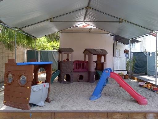 Playground with sand, play structures, and slides under a canopy