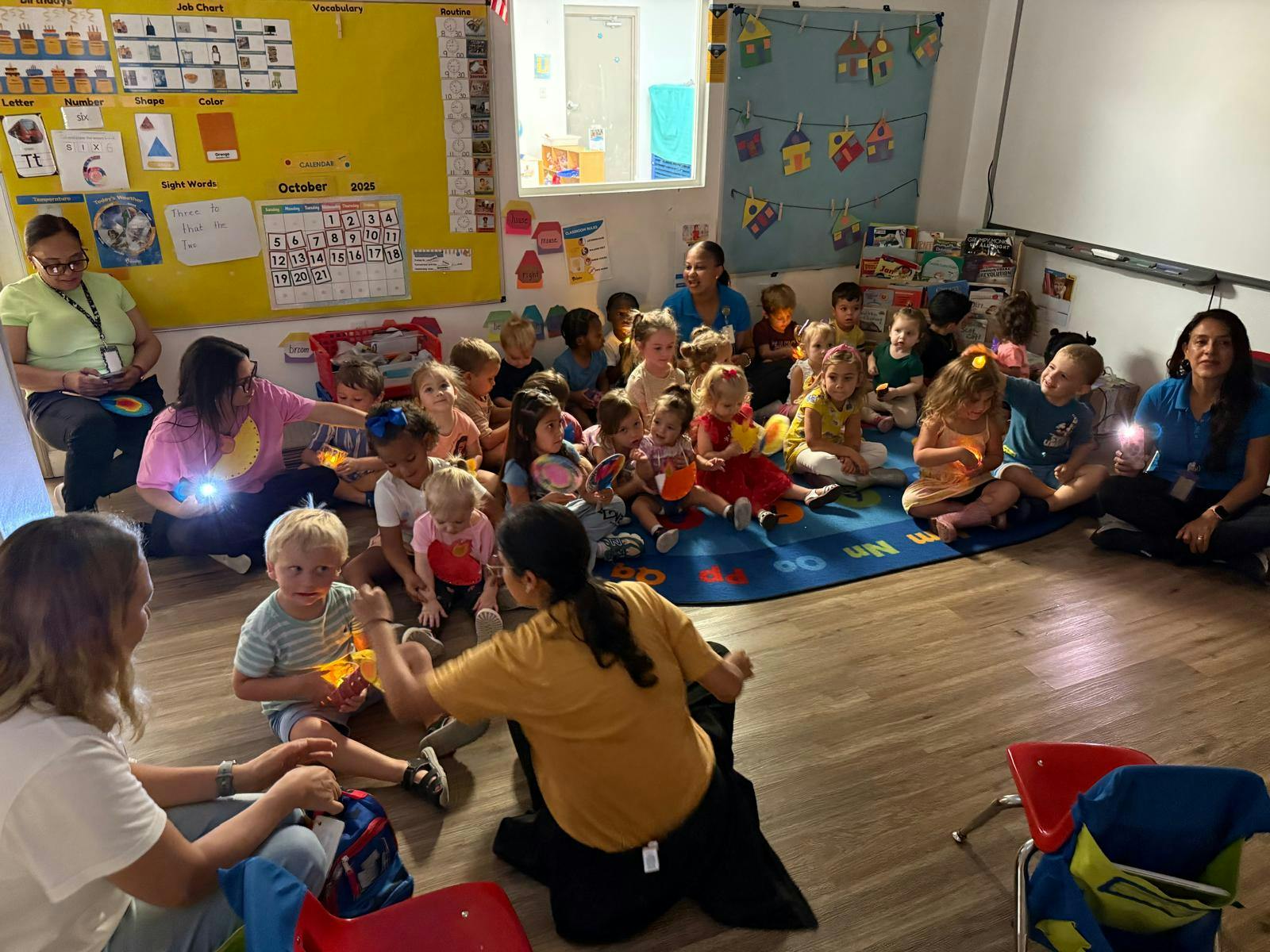 People sitting on a classroom rug with illuminated toys