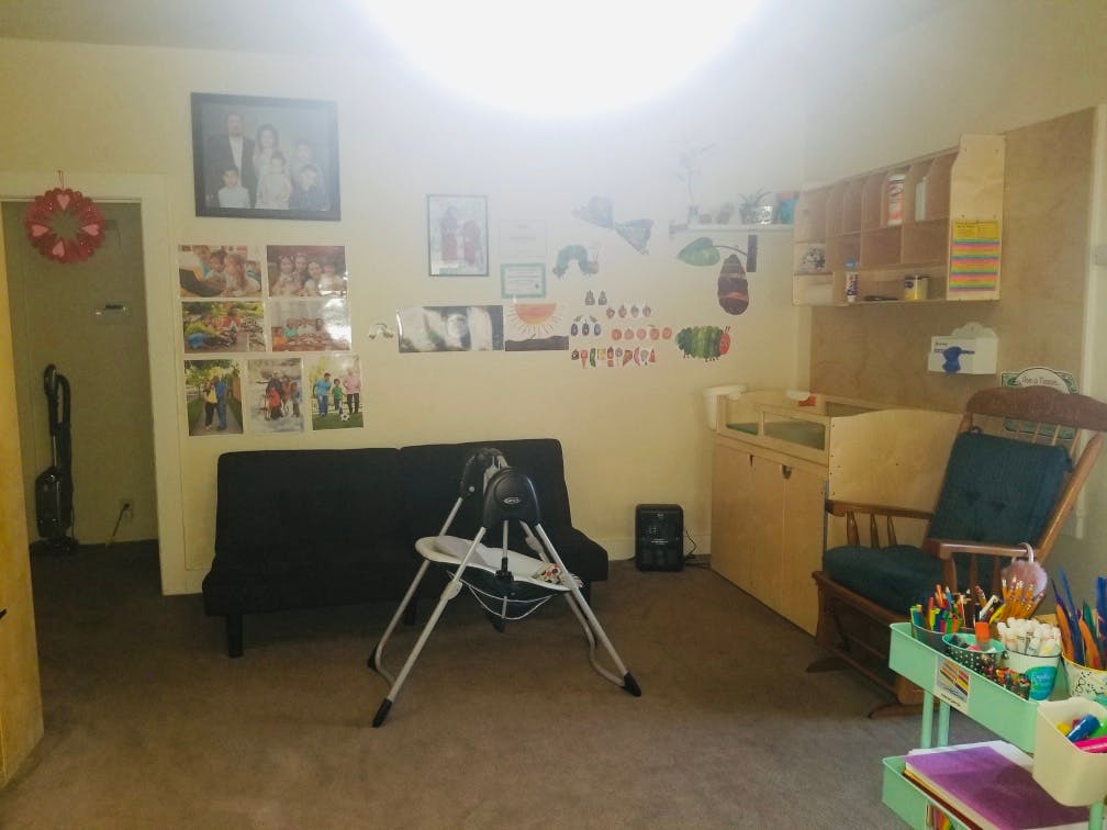 Living area with a black futon, high chair, and rocking chair